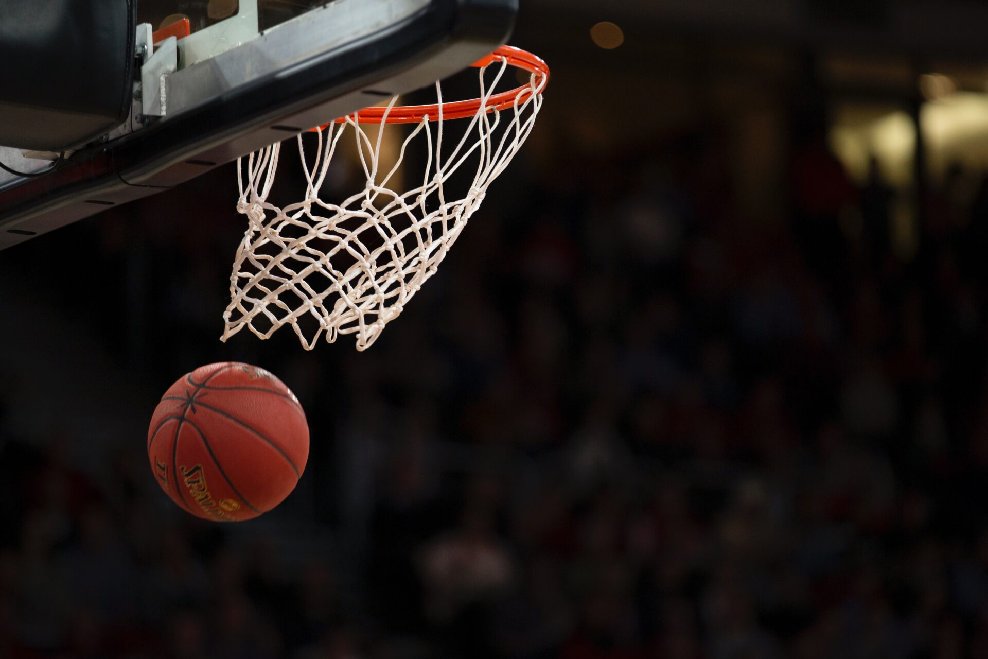 A basketball going through the mesh of a hoop.